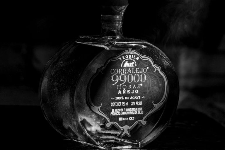 Botella de tequila añejo sobre fondo oscuro, en blanco y negro